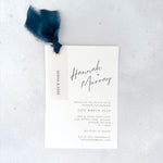 Navy Hannah wedding invite with vellum name tag, metal eyelet, and tied silk ribbon