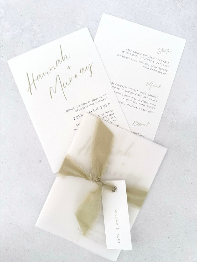 Sage green Hannah vellum wrap wedding invite with tied silk ribbon and guest name tag. Insert card for wedding info and menu options. Handmade by Zara