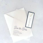transparent vellum save the date card with navy date tag and gold teardrop paperclip