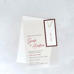 transparent vellum wedding invite with burgundy name tag and teardrop paperclip