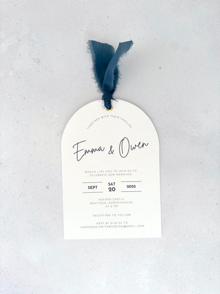 Handmade Emma arched wedding invite with navy silk ribbon and metal eyelet