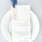 Handmade wedding day menu with dusky cornflower blue silk ribbon, vellum tag, and golf metal eyelet