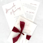 Burgundy Hannah wedding invitation with tied silk ribbon and transparent vellum jacket. Guest name tag with metal eyelet.  Insert card for wedding info and menu options. 