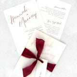 Burgundy Hannah wedding invitation with tied silk ribbon and transparent vellum jacket. Guest name tag with metal eyelet.  Insert card for wedding info and menu options. 