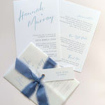 Pale blue Hannah wedding invitation with tied silk ribbon and transparent vellum jacket. Guest name tag with metal eyelet.  Insert card for wedding info and gift wishes