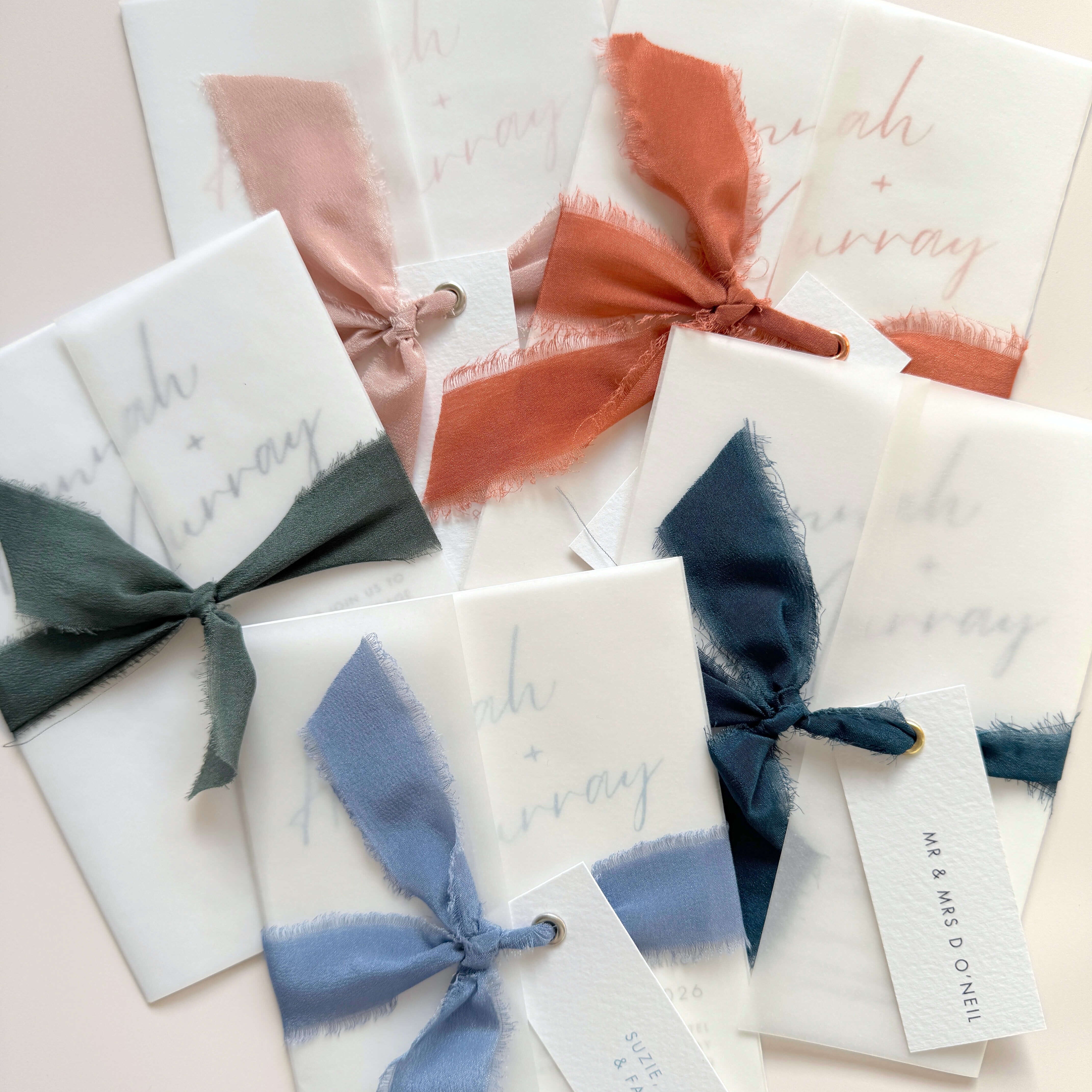 See through vellum wrapped wedding invitations with silk ribbons and guest name tags