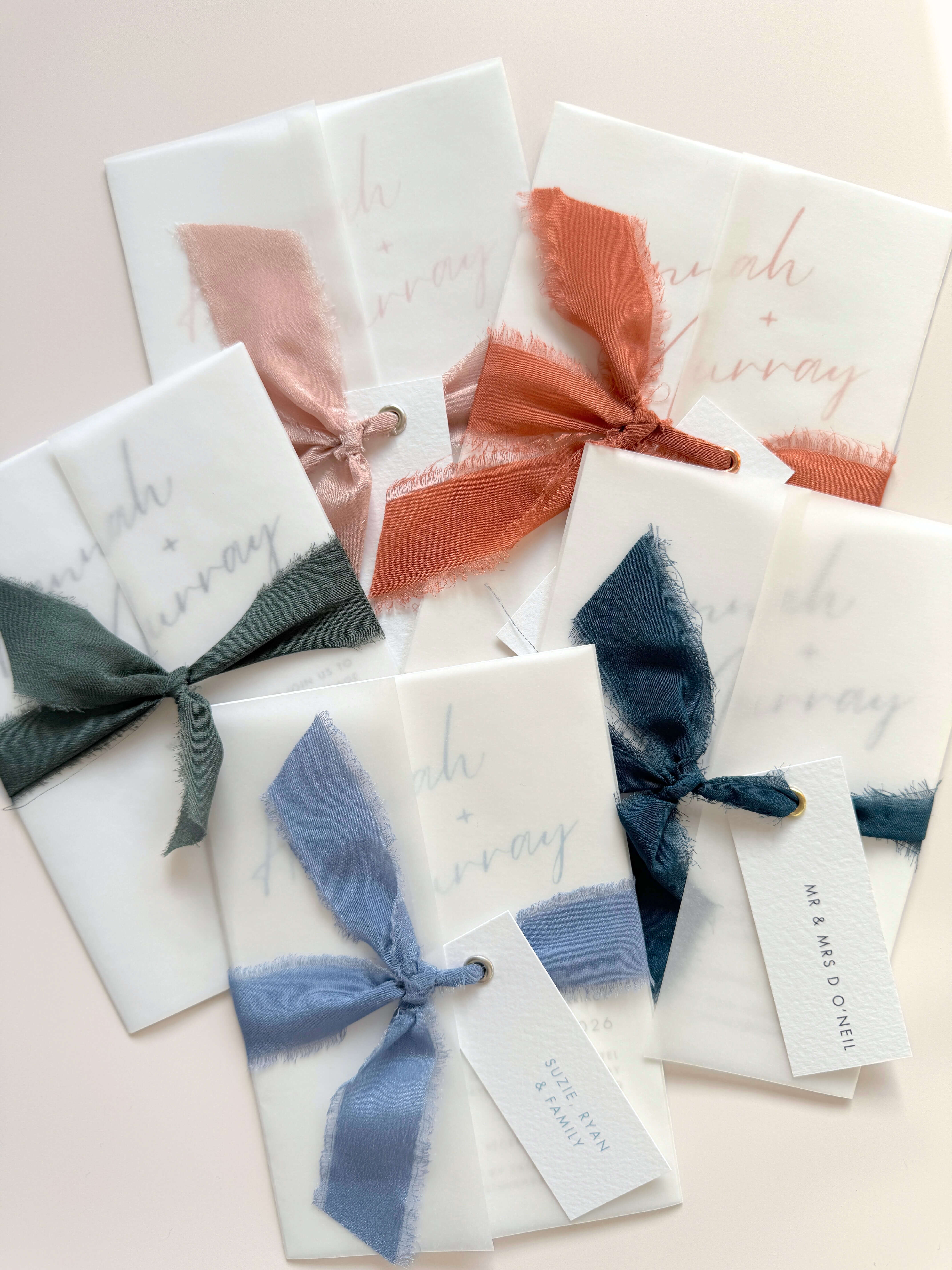 See through vellum wrapped wedding invitations with silk ribbons and guest name tags
