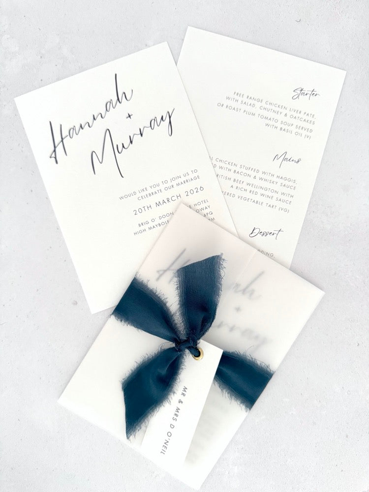 Navy Hannah wedding invitation with tied silk ribbon and transparent vellum jacket. Guest name tag with metal eyelet.  Insert card for wedding info and menu options. 