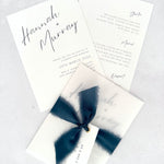 Navy Hannah wedding invitation with tied silk ribbon and transparent vellum jacket. Guest name tag with metal eyelet.  Insert card for wedding info and menu options. 