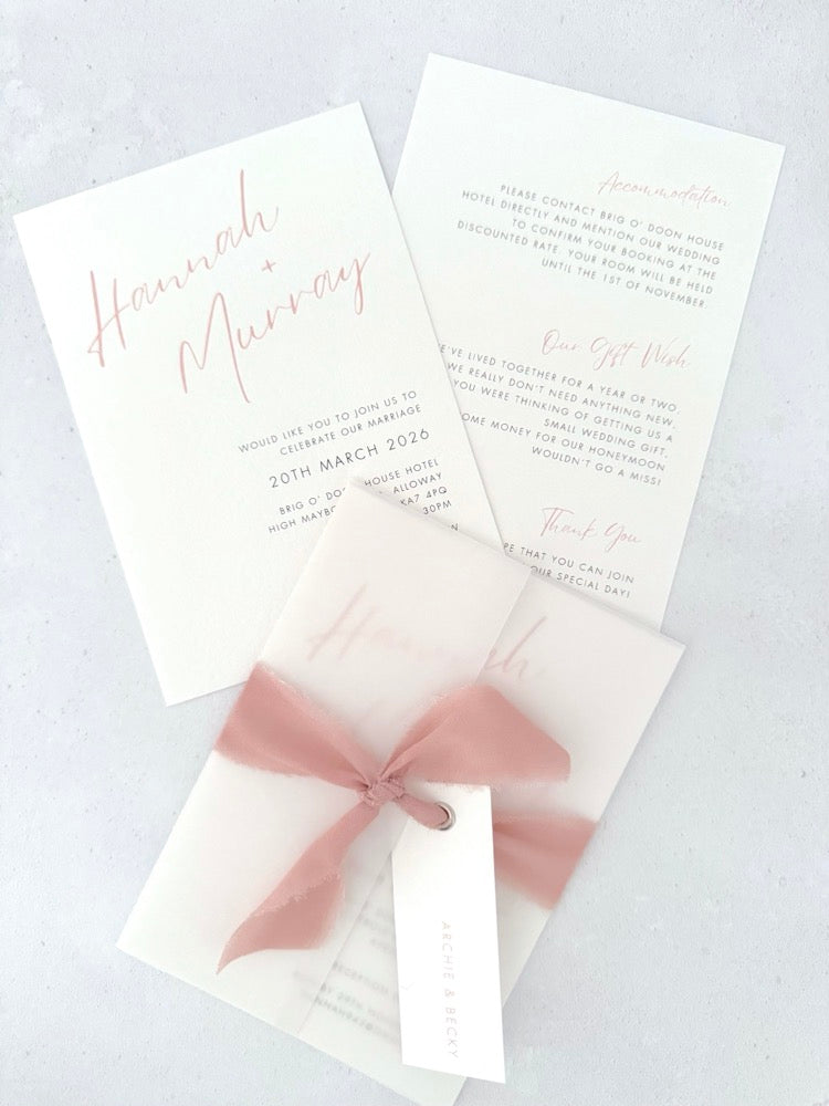 Blush Pink Hannah wedding invitation with tied silk ribbon and transparent vellum jacket. Guest name tag with metal eyelet.  Insert card for wedding info and menu options. 