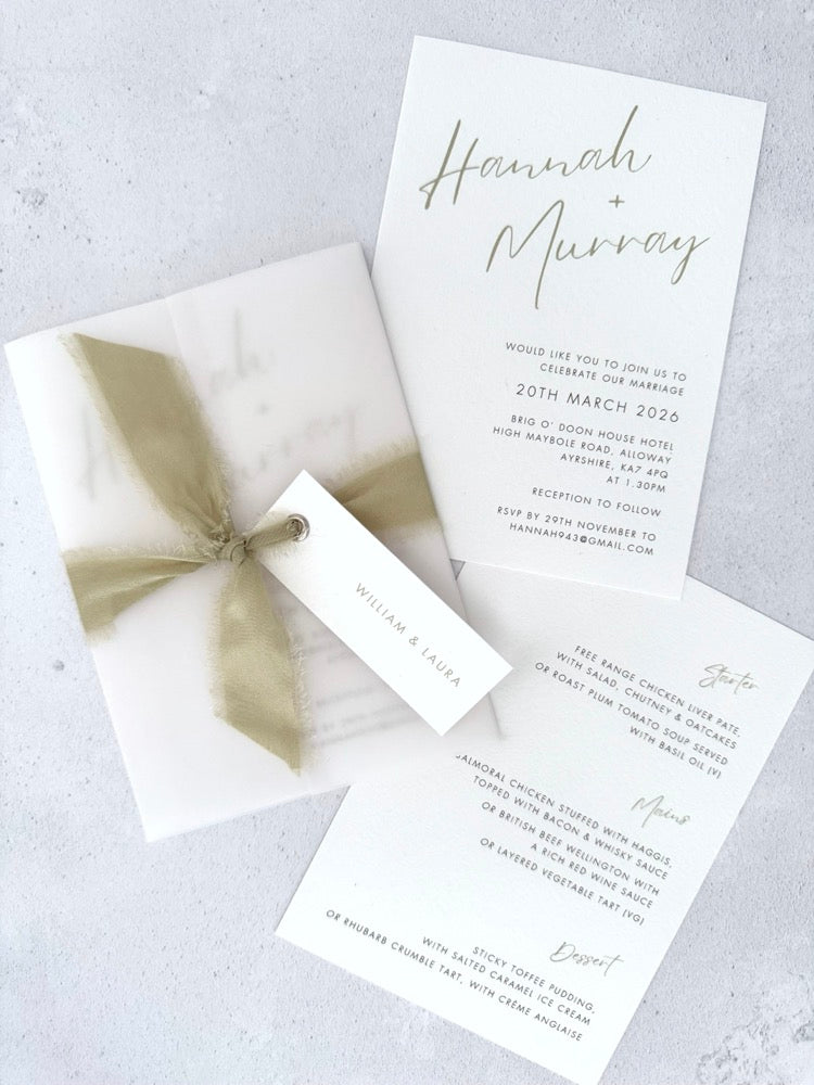 Sage green Hannah wedding invitation with tied silk ribbon and transparent vellum jacket. Guest name tag with metal eyelet.  Insert card for wedding info and menu options. 