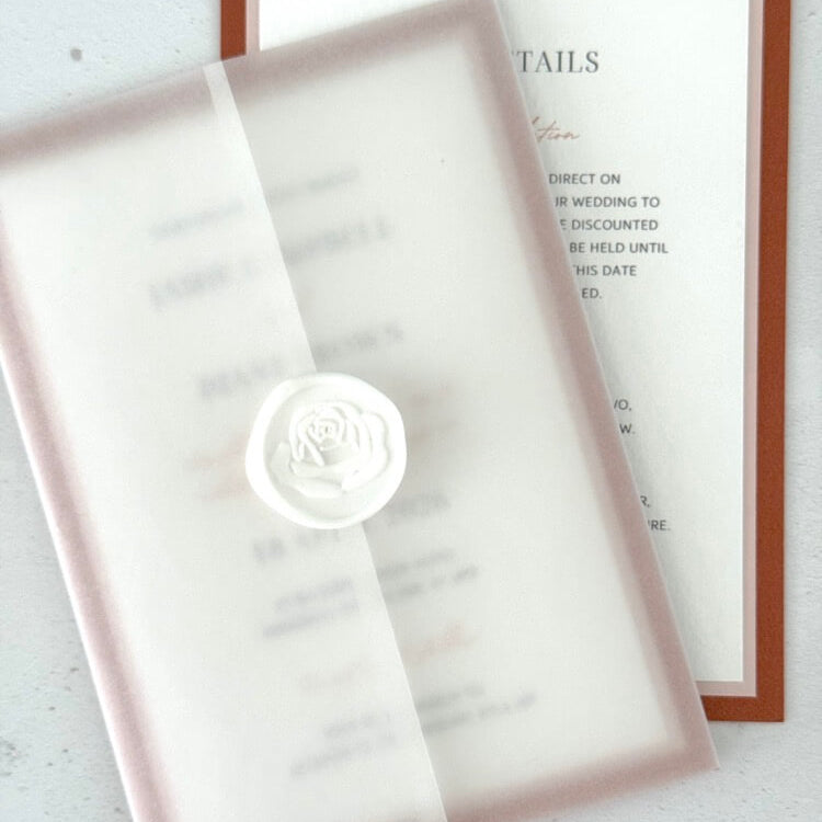 Layered wedding invitation held in a vellum wrap secured white rose wax seal