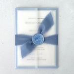 Transparent vellum wedding invite in dusty blue with tied silk ribbon and wax seal