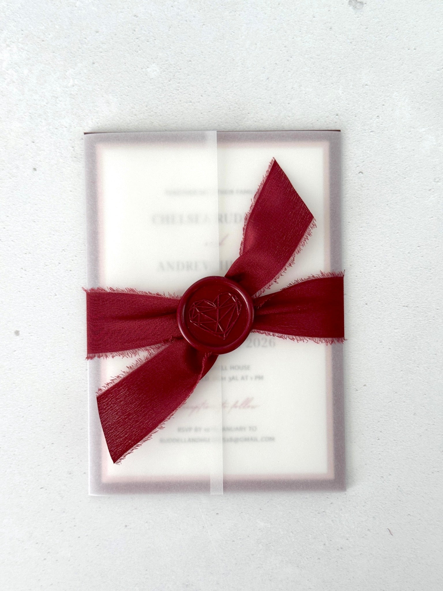 Burgundy wedding invite with transparent vellum paper wrap and ribbon bow