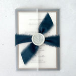 See thru vellum paper wrapped wedding invitation with navy silk ribbon and wax seal