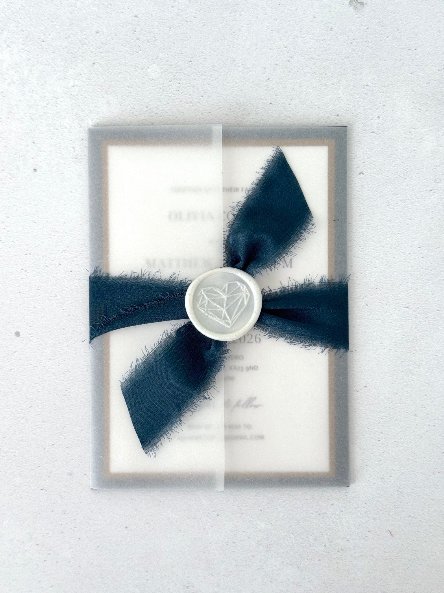 See thru vellum paper wrapped wedding invitation with navy silk ribbon and wax seal