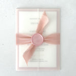 Transparent vellum paper wrapped wedding invite with pink silk ribbon and wax seal