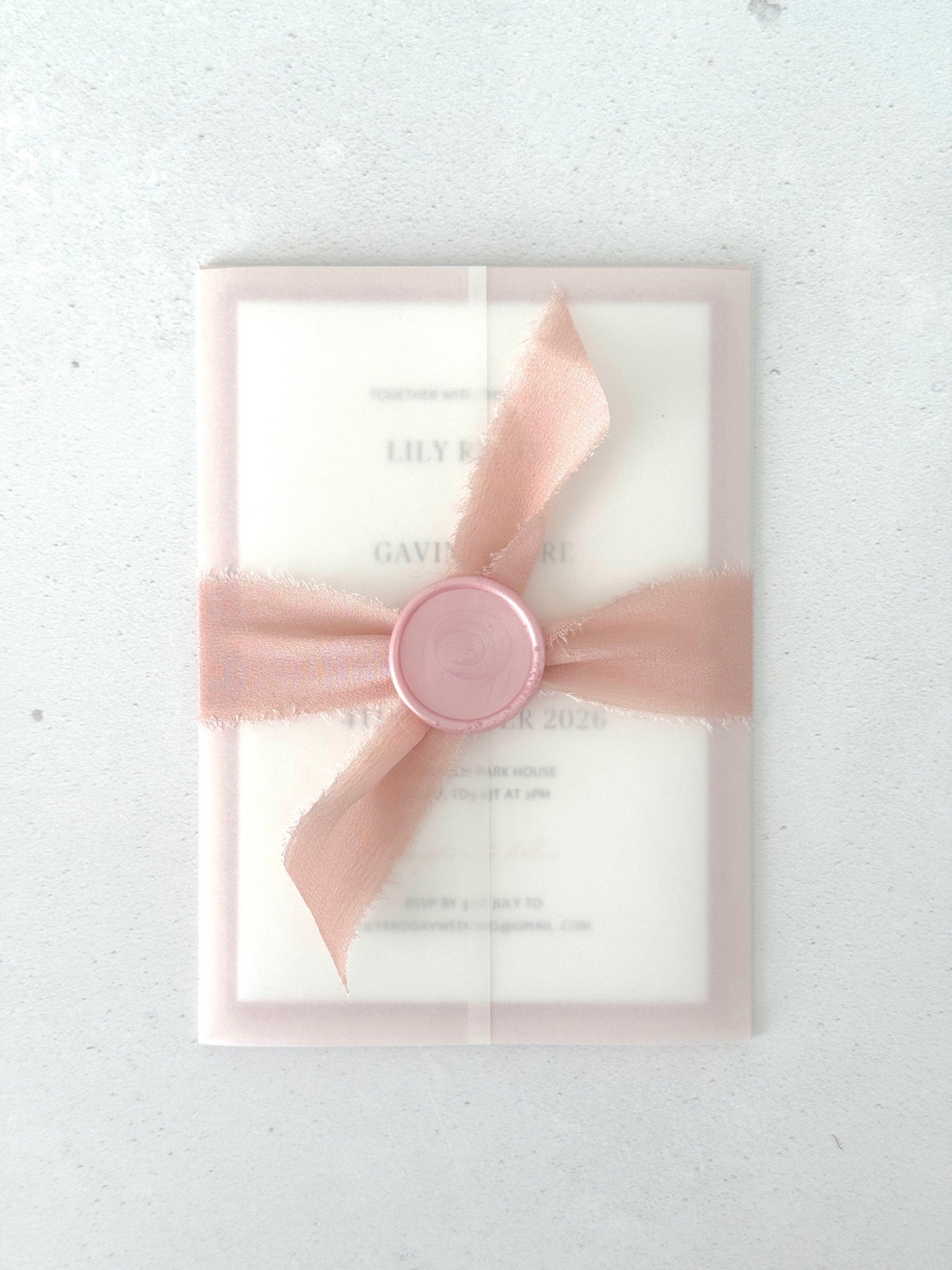 Transparent vellum paper wrapped wedding invite with pink silk ribbon and wax seal