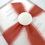 Layered wedding invitation held in a vellum wrap secured with a silk ribbon and wax seal