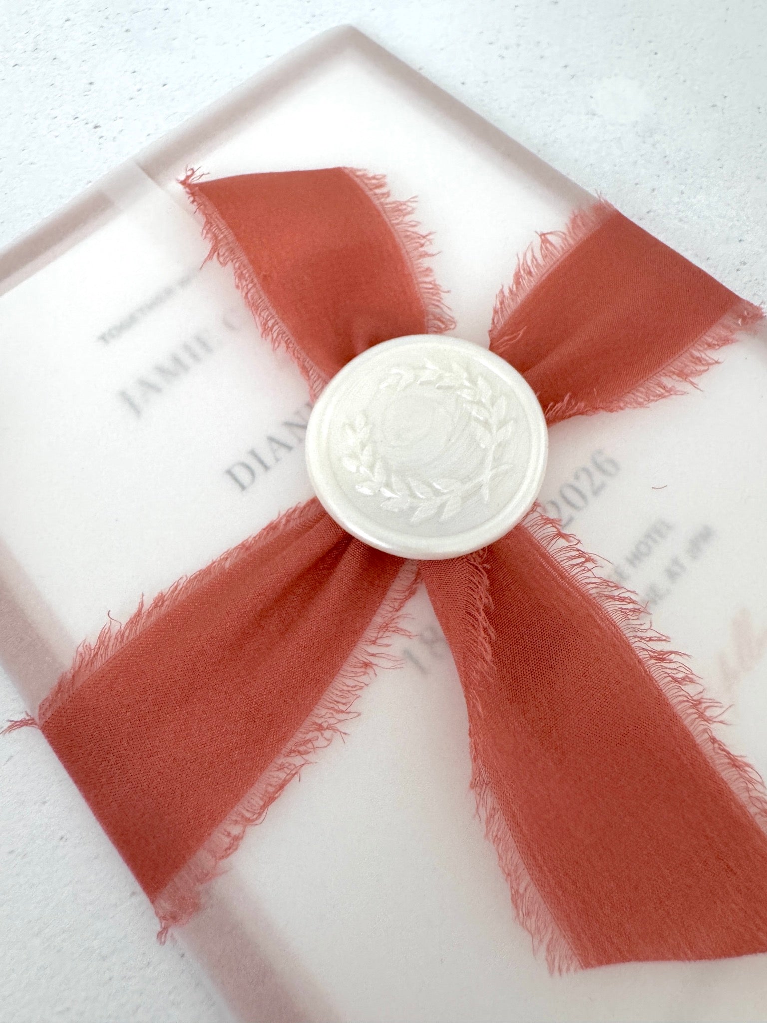 Layered wedding invitation held in a vellum wrap secured with a silk ribbon and wax seal