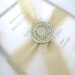 handmade wreath wax seal in sage green with tied silk ribbon around see through vellum wrap wedding invite