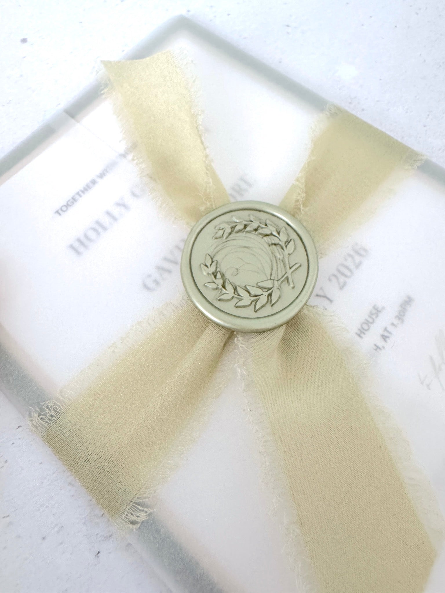 handmade wreath wax seal in sage green with tied silk ribbon around see through vellum wrap wedding invite