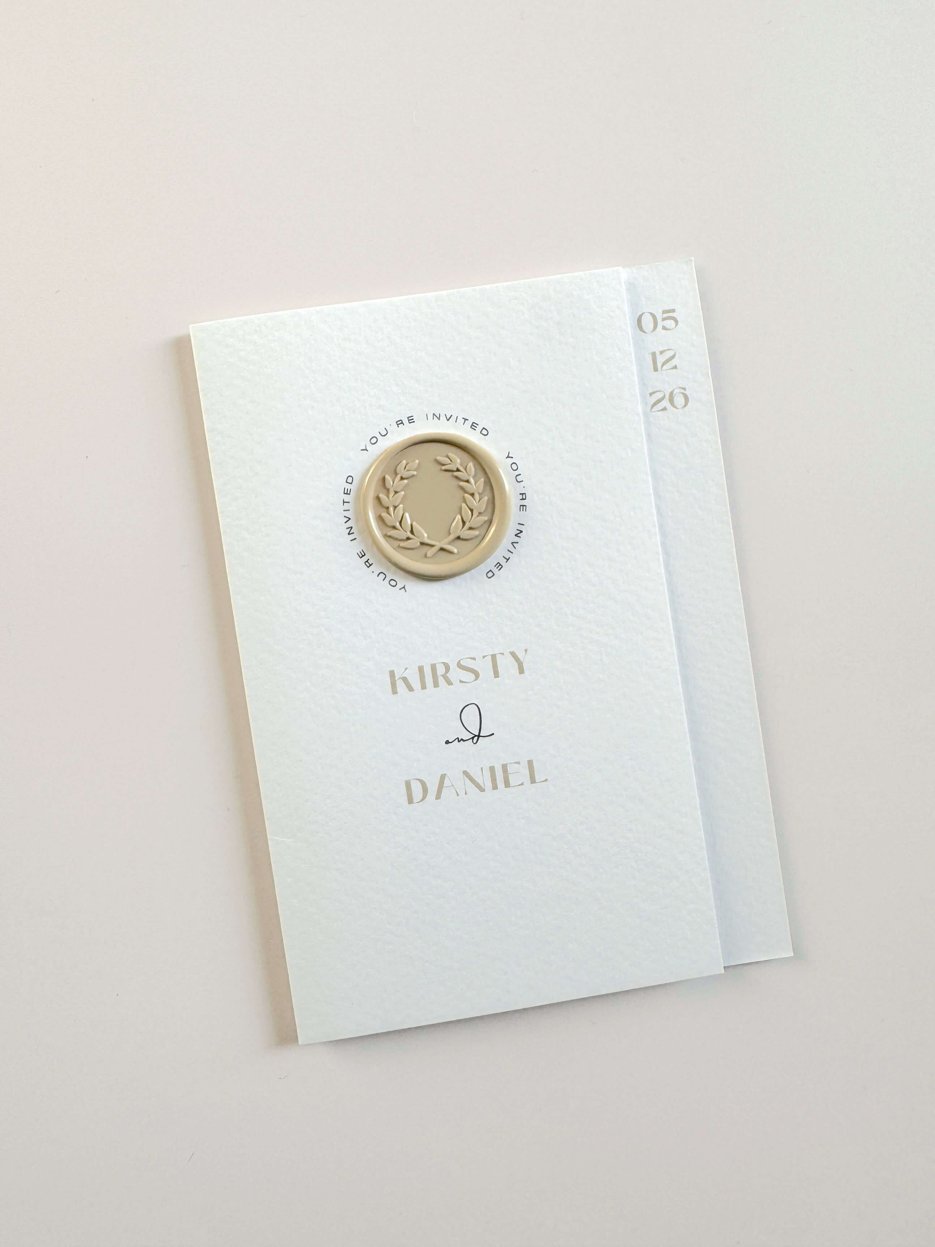 Kirsty folded wedding invite with neutral wreath wax seal