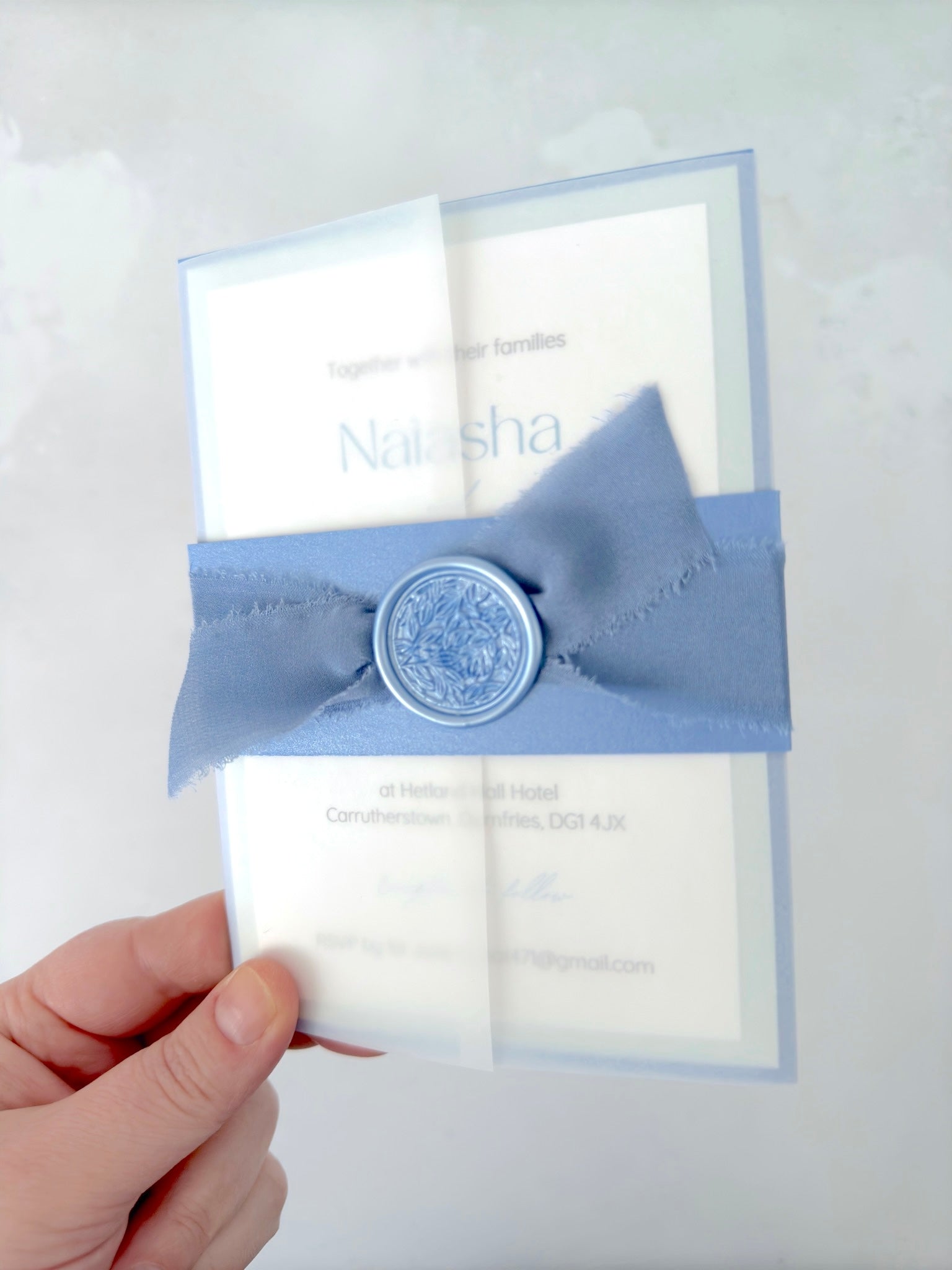 Lyn vellum wrap wedding invite with dusky blue belly band, silk ribbon, and waxs seal