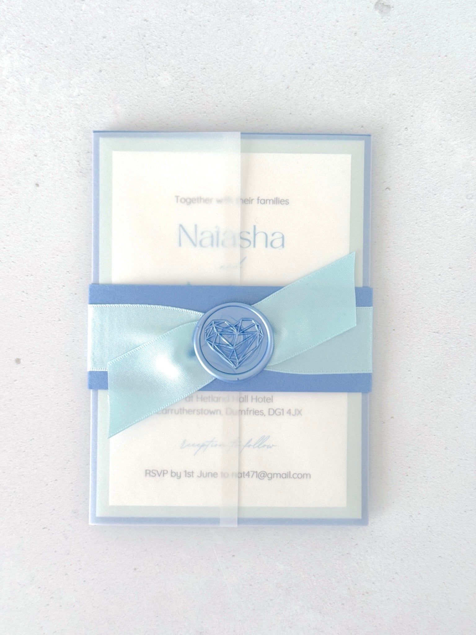 Wedding invite with dusty blue belly band and transparent paper wrap