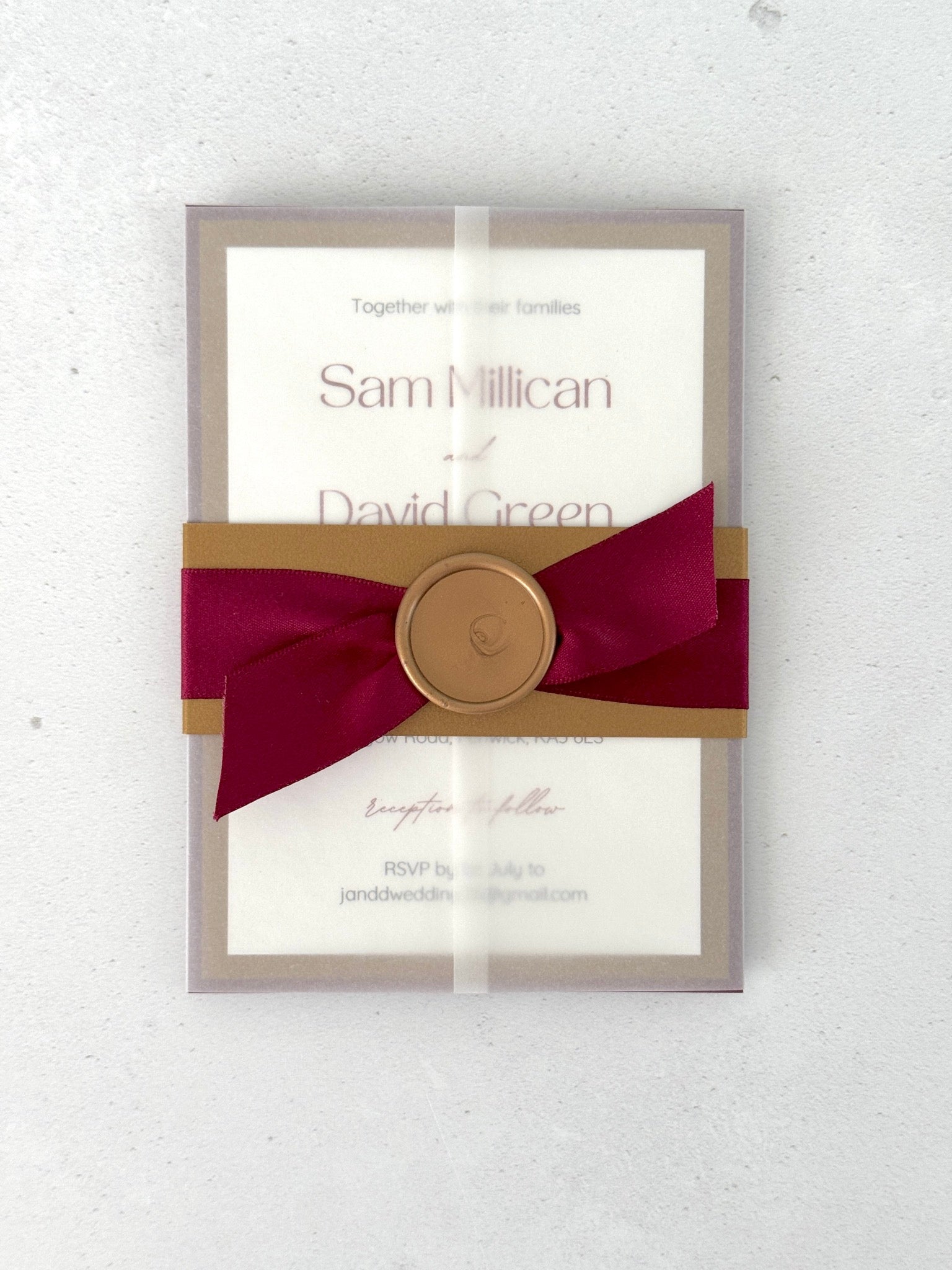 Gold and burgundy red belly band on see thru paper wrapped wedding invite