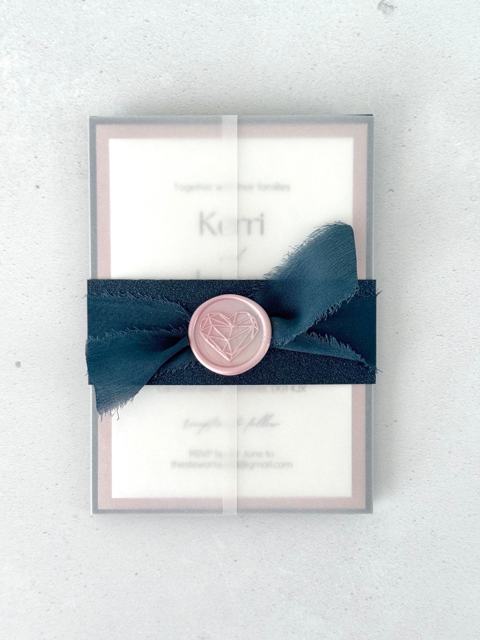 see thru paper wrapped wedding invite with navy belly band and pink wax seal