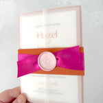 Lyn wedding invite with rust orange belly band and bright pink satin ribbon, pink wax seal, in a vellum wrap