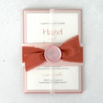 see through paper wrapped wedding invite with pink belly band and handmade wax seal with orange silk ribbon