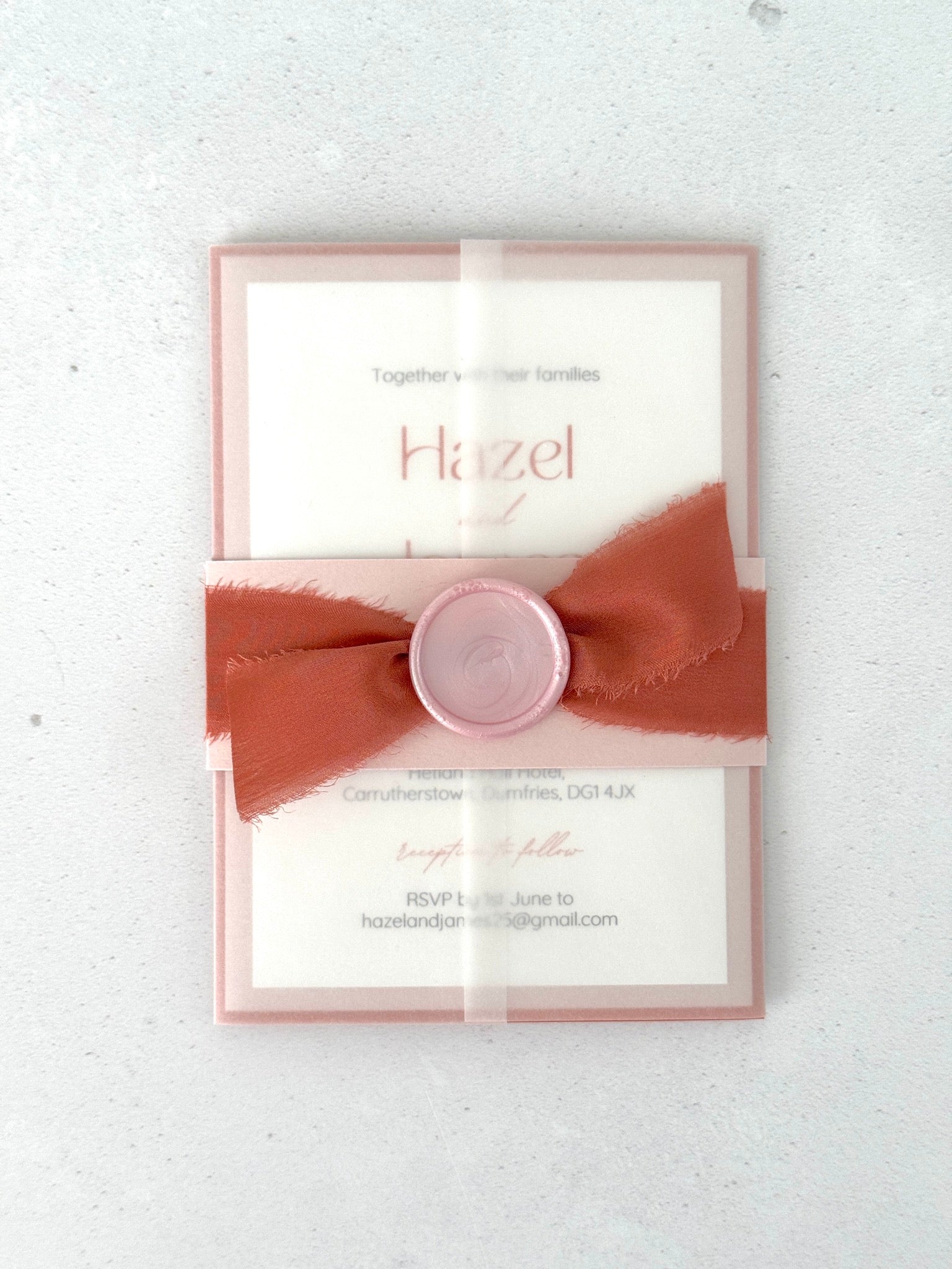 see through paper wrapped wedding invite with pink belly band and handmade wax seal with orange silk ribbon