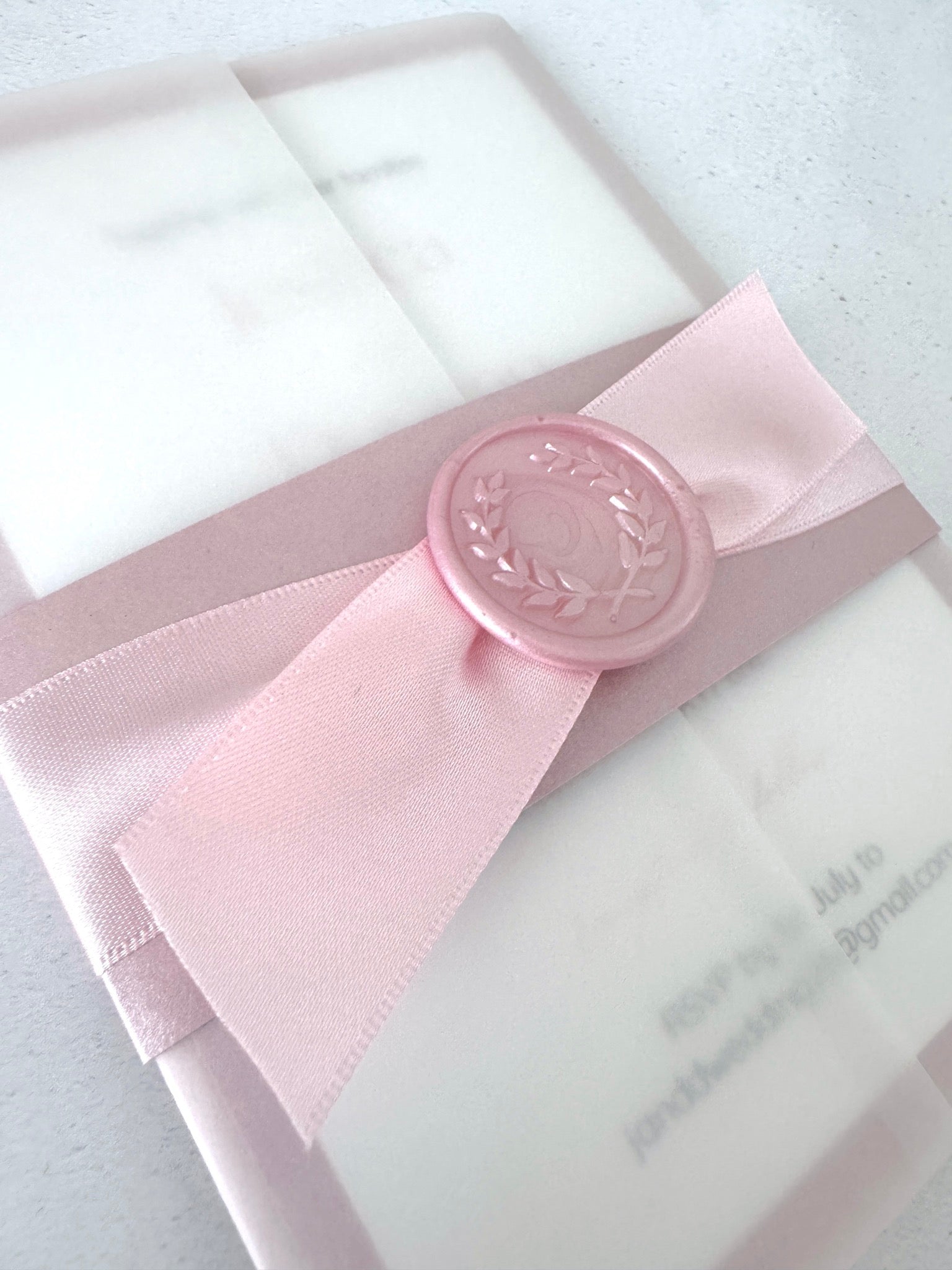 misty rose pink belly band with satin ribbon and wax seal vellum wrap wedding invite