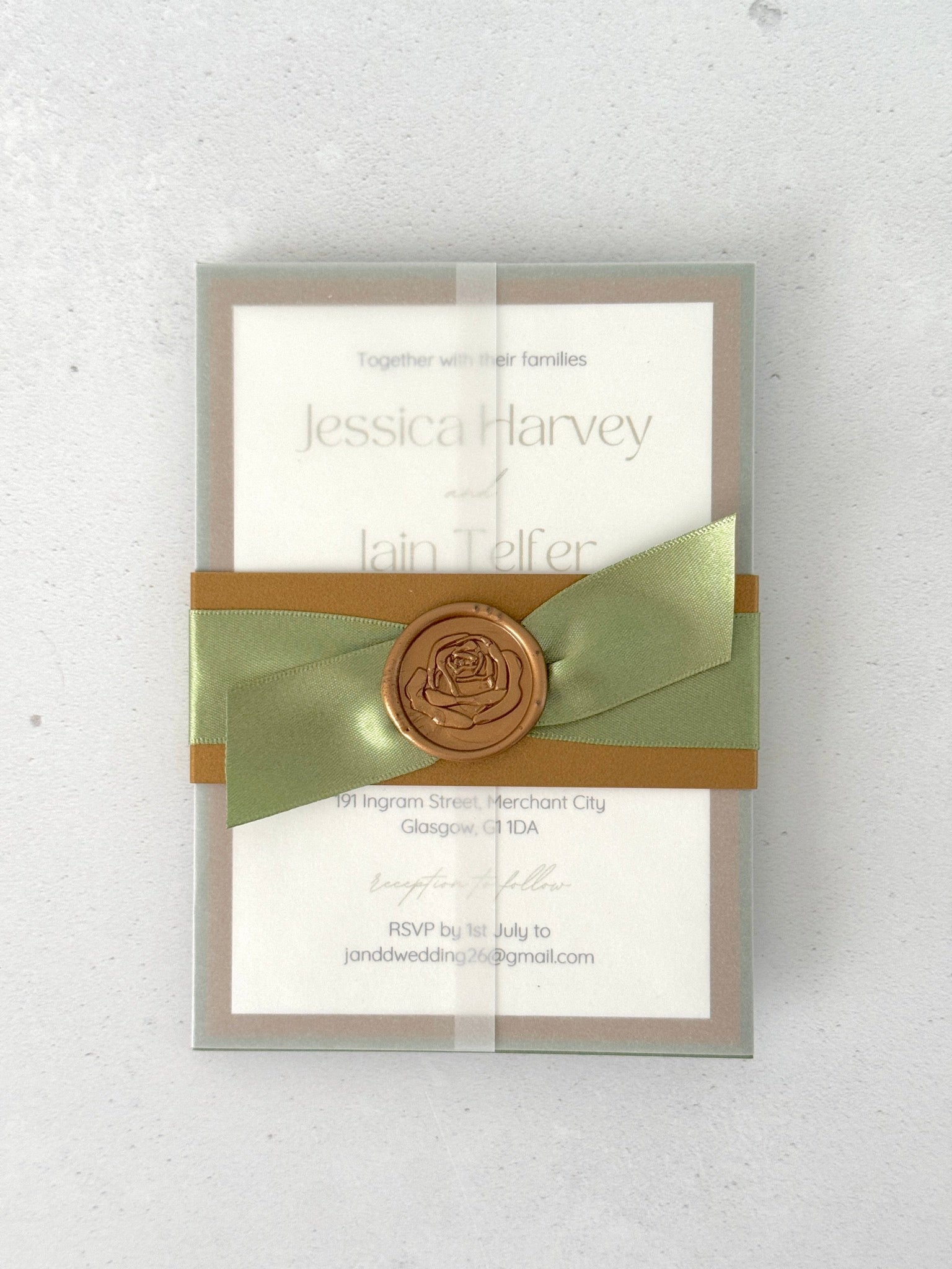 transparent wrapped wedding invite with belly band and wax seal in sage green and gold