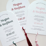 Three arch shaped textured white wedding invitations  with tassels 