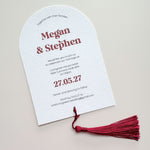 Burgundy red tassel on arches shaped wedding invite with  bold modern typography names