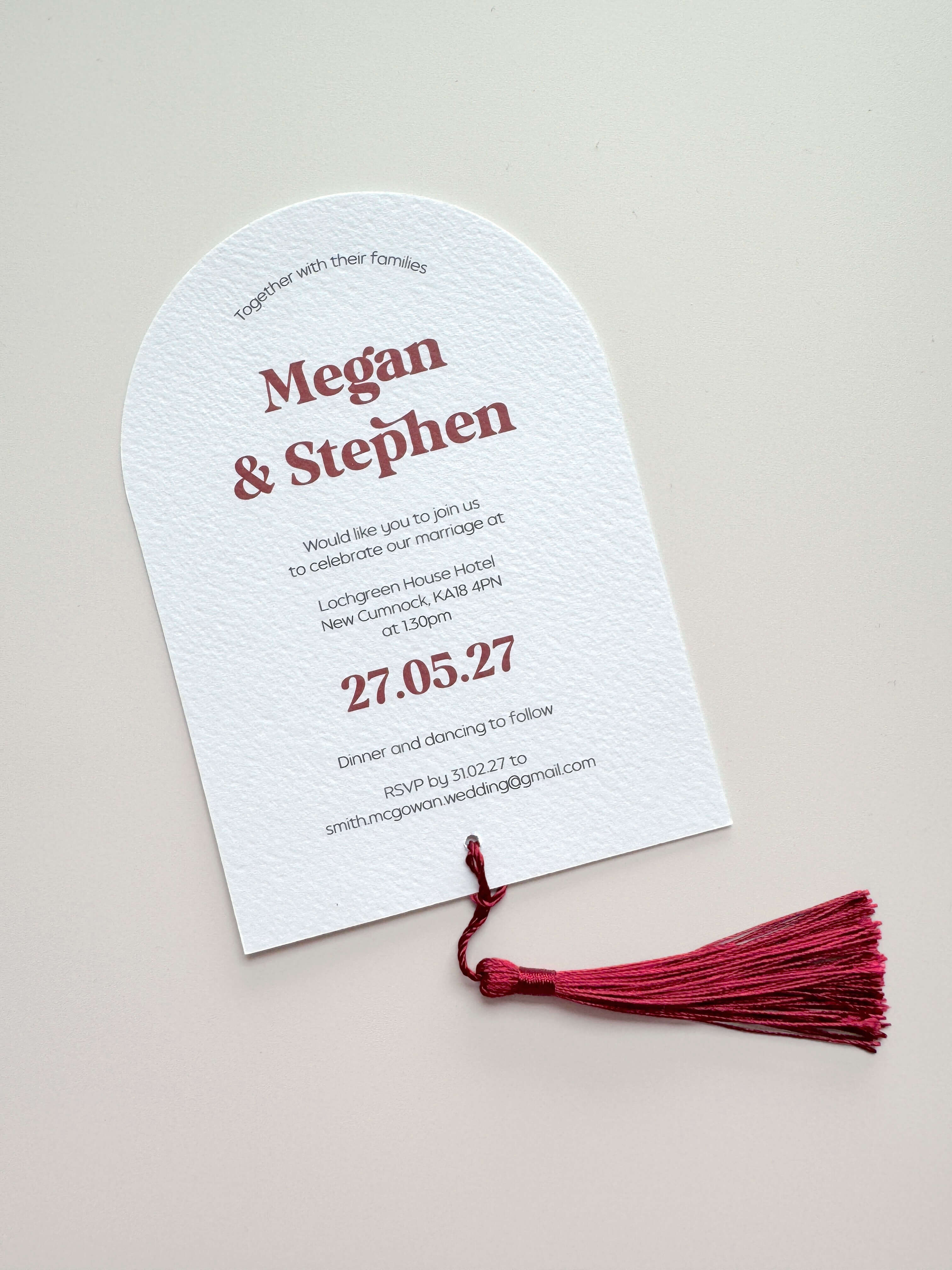 Burgundy red tassel on arches shaped wedding invite with  bold modern typography names