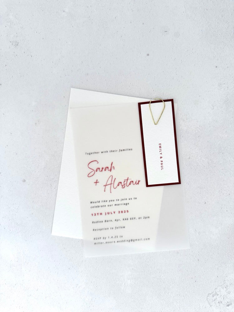 transparent vellum wedding invite with burgundy name tag and teardrop paperclip 