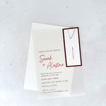 transparent vellum wedding invite with burgundy name tag and teardrop paperclip 