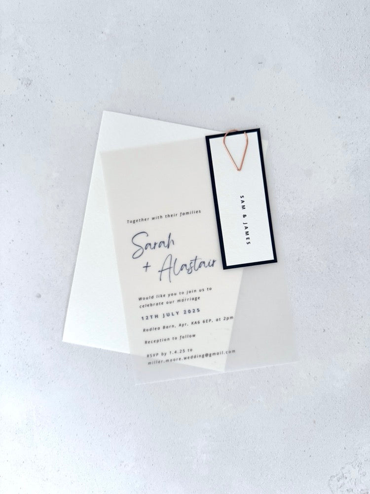 transparent vellum wedding invite with navy name tag and rose gold teardrop paperclip