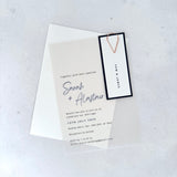 transparent vellum wedding invite with navy name tag and rose gold teardrop paperclip