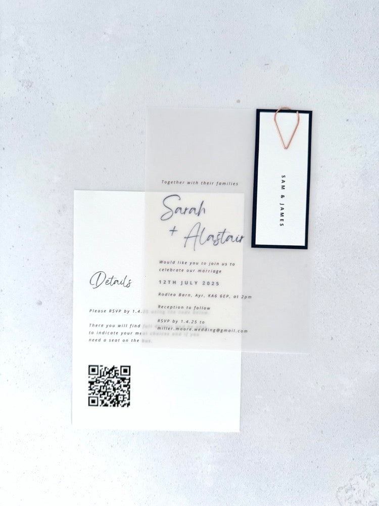 transparent vellum wedding invite with navy name tag and teardrop paperclip and details card with QR code
